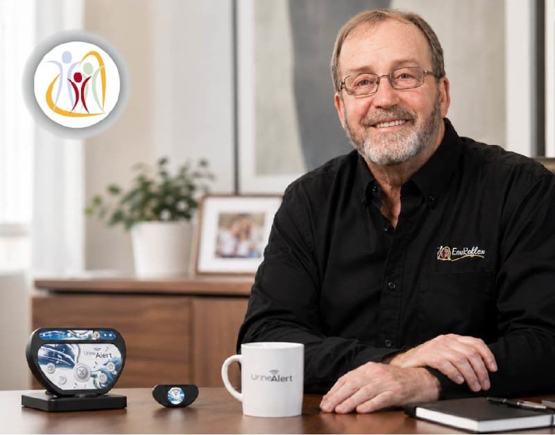 Sylvain Morin, fondateur d’Enureflex, souriant dans son bureau avec le récepteur et le transmetteur Urine-Alert.