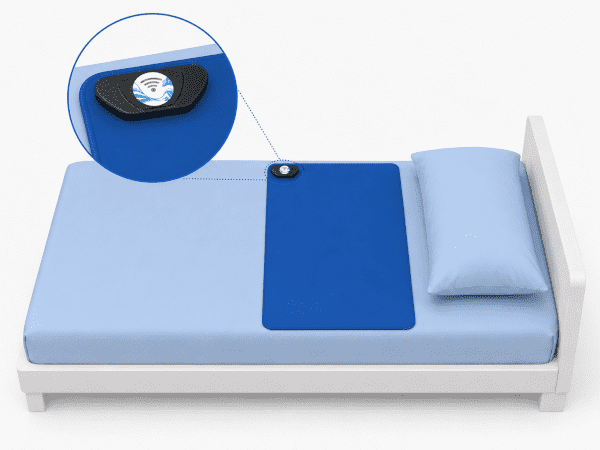 Tapis de détection Urine-Alert installé sur le lit Tapis de détection bleu sur un lit avec transmetteur Urine-Alert fixé dans le coin