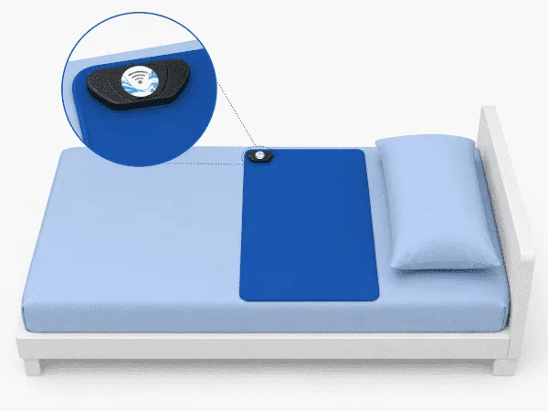 Tapis de détection bleu sur un lit avec transmetteur Urine-Alert fixé dans le coin